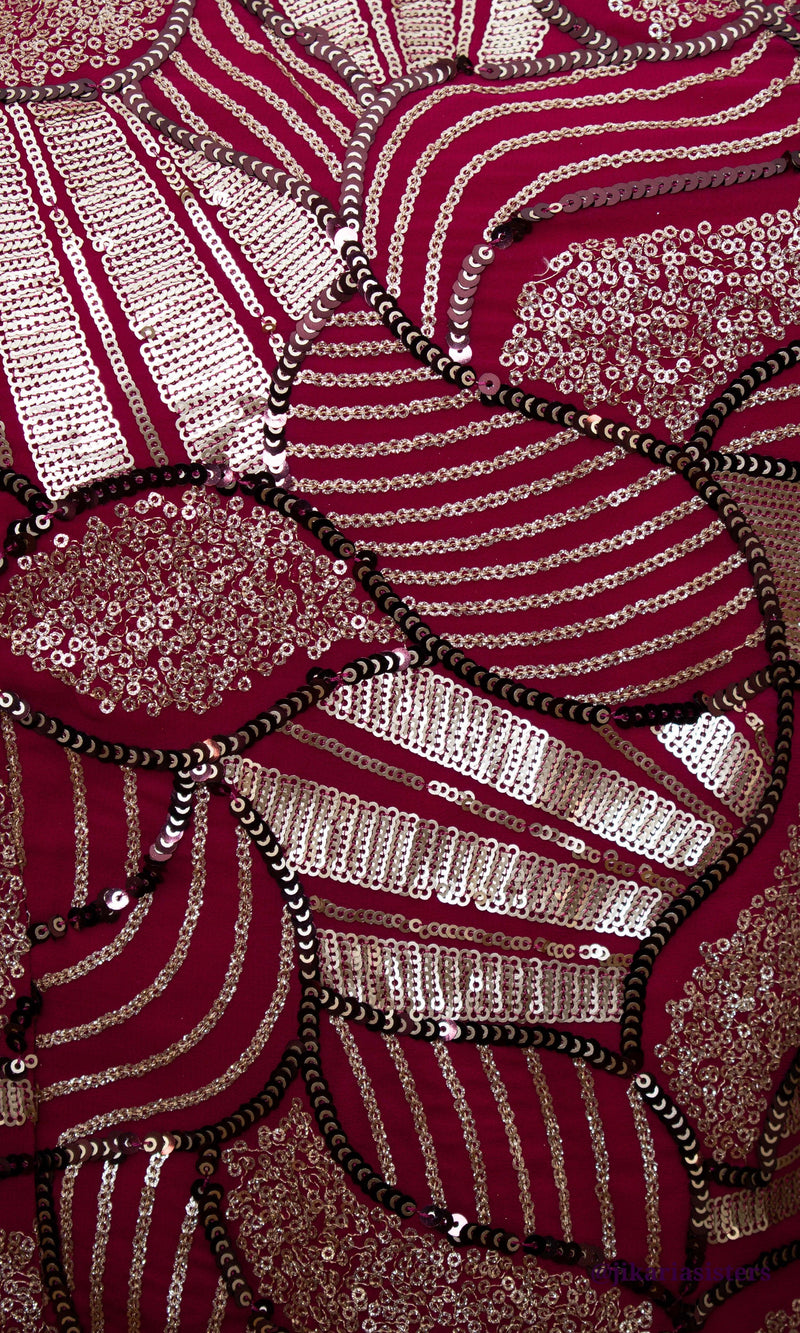 Close-up of a red georgette dress with intricate gold and black sequin embroidery.
