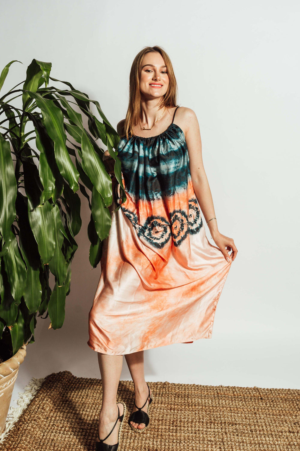 Silk tie-dye midi dress with teal bodice, peach hem, circular motifs, spaghetti straps, and gathered neckline.
