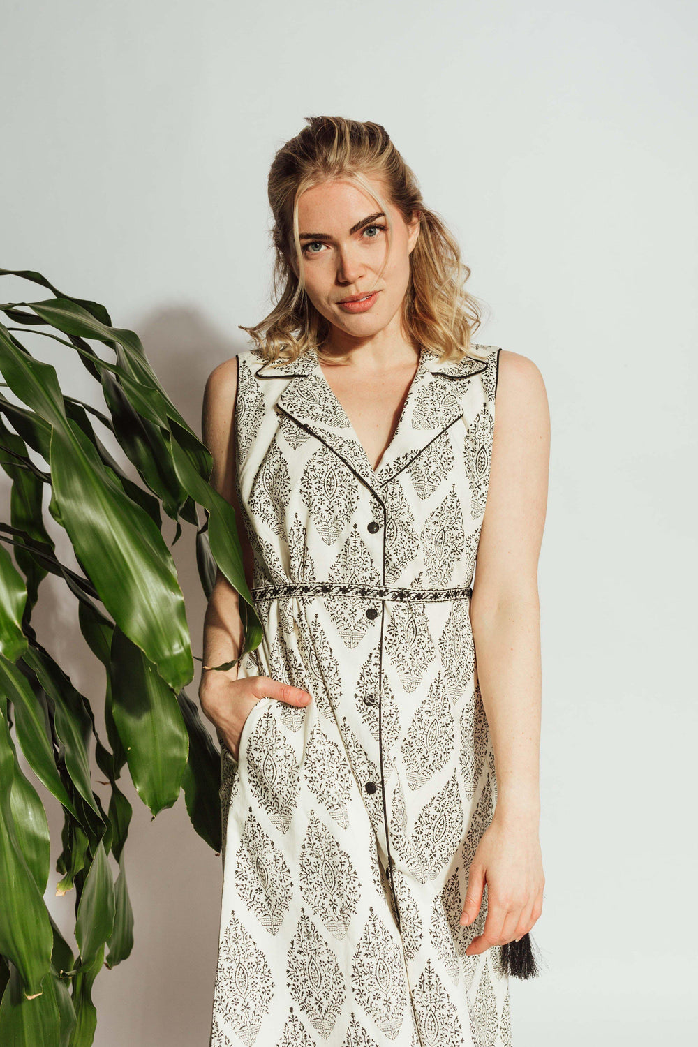 White cotton blazer dress with dark floral block-print, notched lapels, and an embroidered drawstring belt.