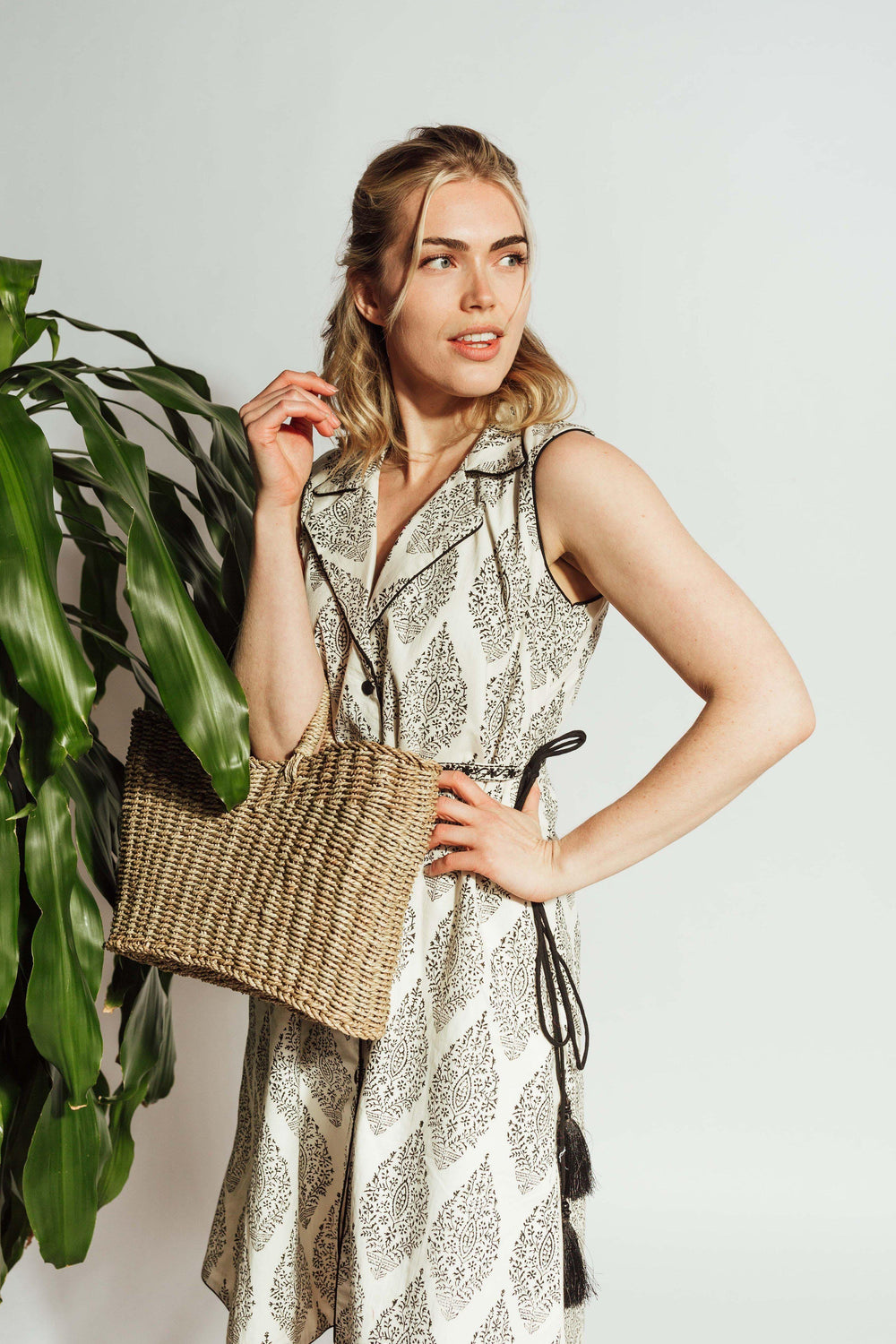White cotton blazer dress with dark floral block-print, sleeveless, notched lapels, and embroidered drawstring belt.