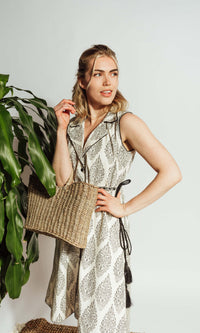 White cotton blazer dress with dark floral block-print, sleeveless, notched lapels, and embroidered drawstring belt.