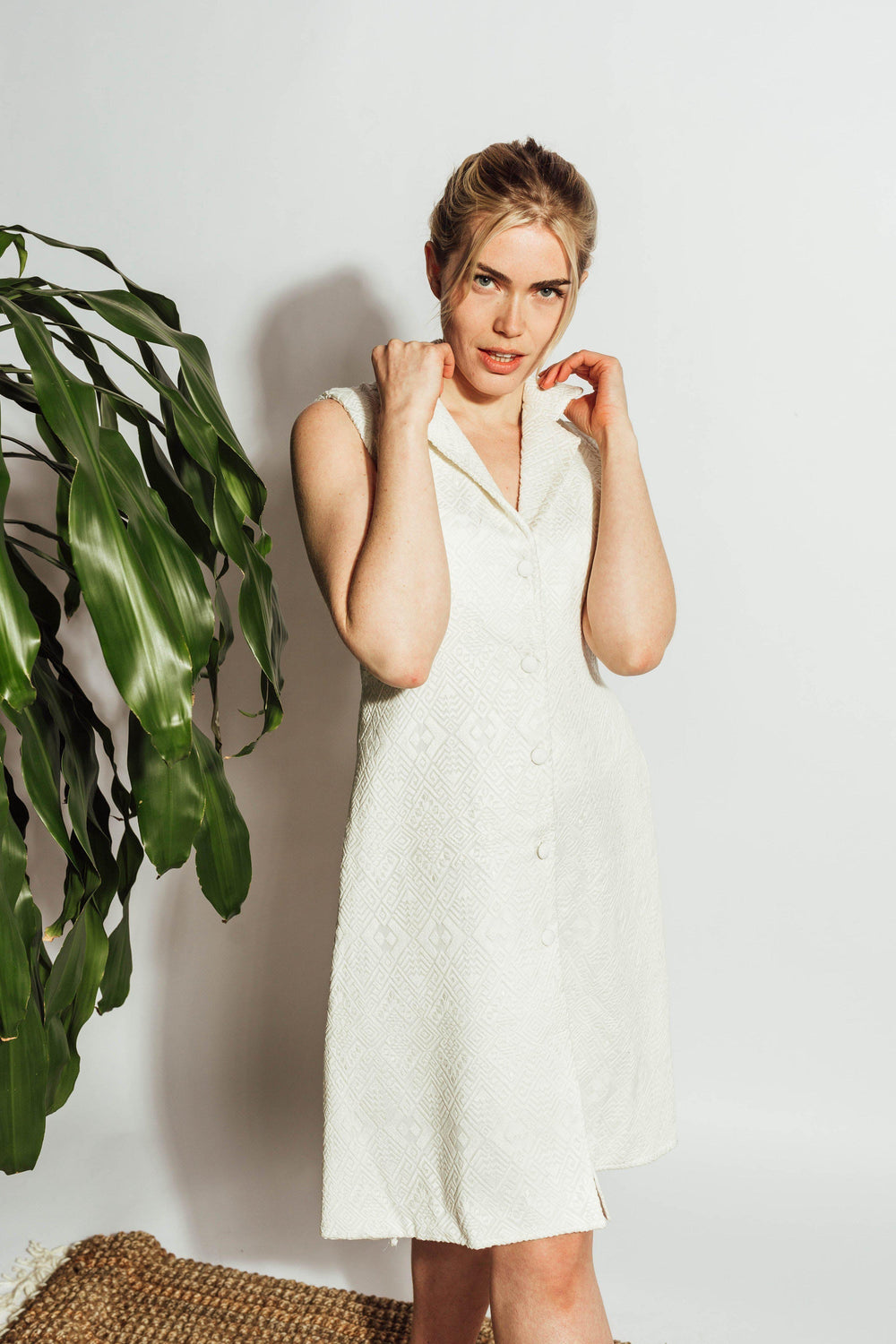 White sleeveless blazer dress with self-thread geometric embroidery, notched lapel, and front buttons.