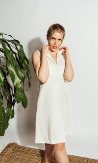 White sleeveless blazer dress with self-thread geometric embroidery, notched lapel, and front buttons.