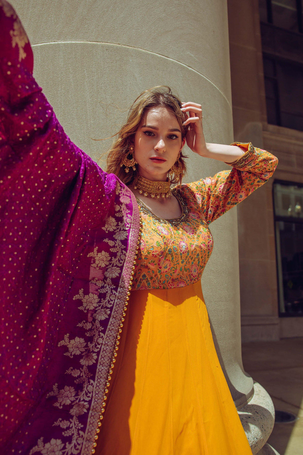 Yellow A-line hand-embroidered gown with multicolor resham work, paired with a magenta silk drape.